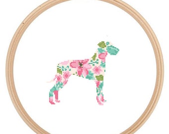 May include: A floral pattern cross-stitch design of a dog in a wooden embroidery hoop. The dog is outlined in pink and green floral patterns.