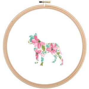 May include: A wooden embroidery hoop with a floral design in pink and green, depicting the silhouette of a dog.