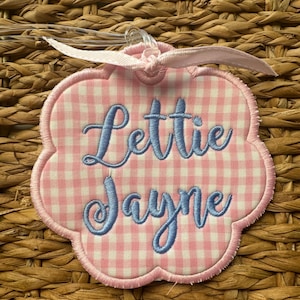May include: Pink and white gingham luggage tag with blue embroidered lettering that reads "Lettie Jayne".