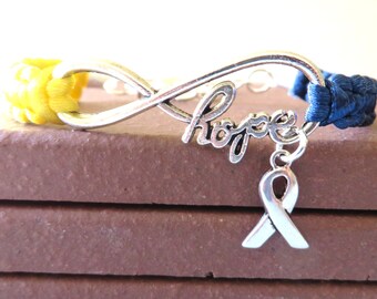 May include: A yellow and blue braided bracelet with an infinity symbol charm that says "hope" and a silver ribbon charm.