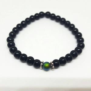 May include: A black beaded bracelet with a single iridescent green bead in the center.