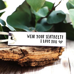 May include: Silver keychain with the text "Wear your seatbelt! I love you" and a small heart.