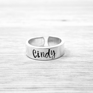 May include: A silver ring with the name "Cindy" engraved on it.