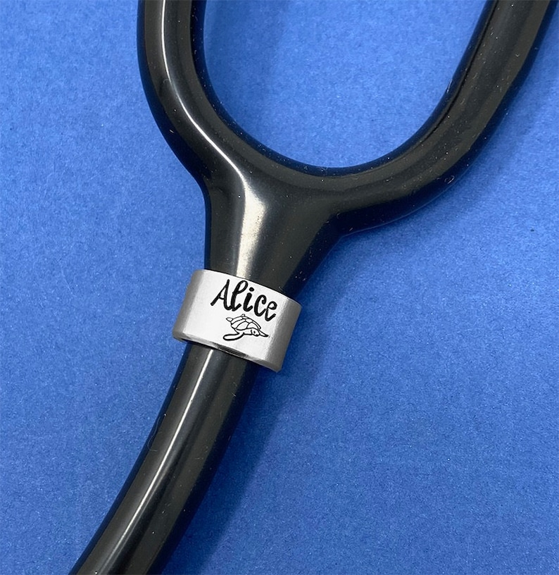 May include: A black stethoscope with a silver charm that says "Alice" and has a small turtle design.