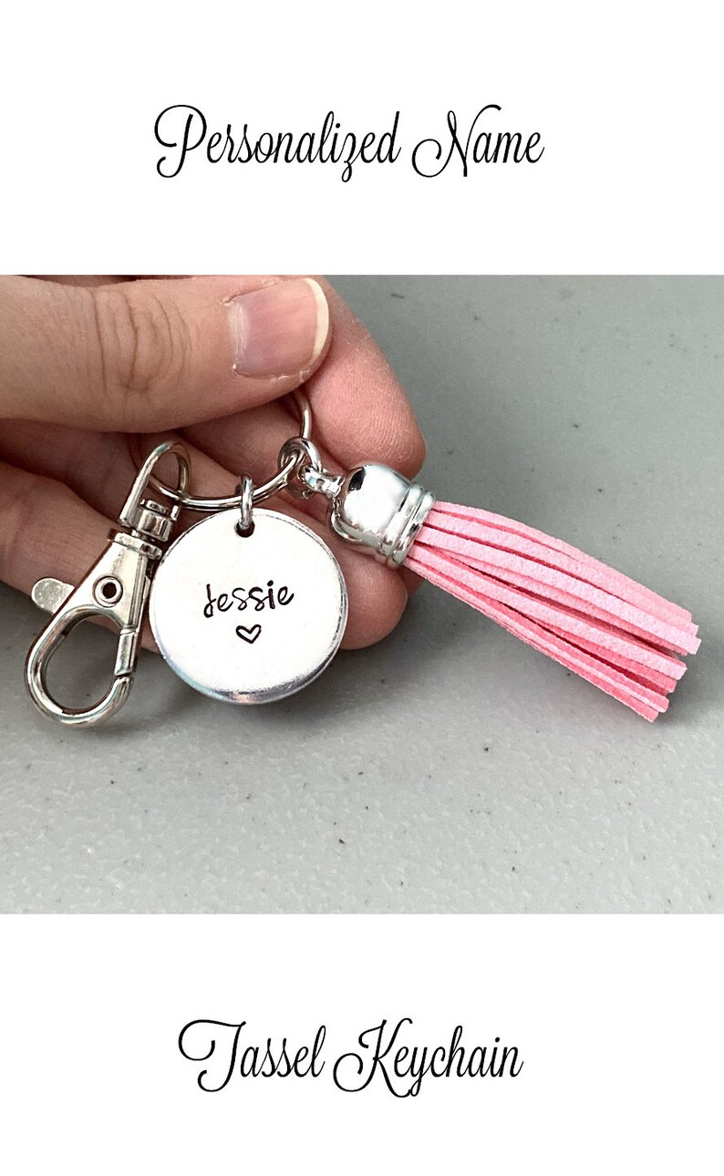 May include: A silver keychain with a pink tassel and a round charm that says "Jessie" with a heart. The keychain is a personalised gift.