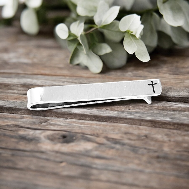 May include: Silver tie bar with a cross engraved on the front.