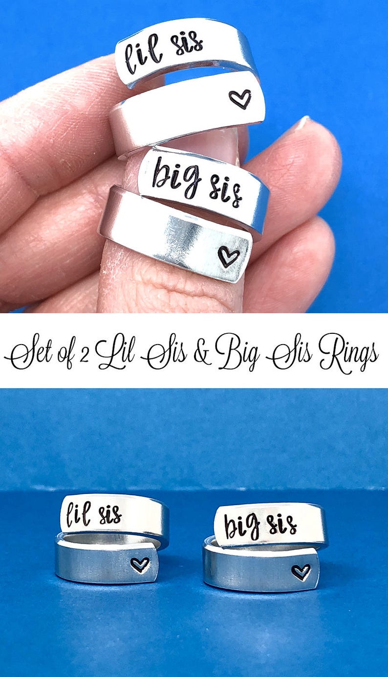 May include: Set of two silver rings with the words "lil sis" and "big sis" engraved on them. Each ring has a small heart engraved on the side.