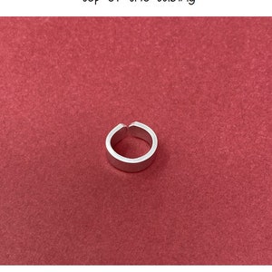 May include: A silver oval-shaped tag designed to fit around the top of a stethoscope. The tag is shown on a red background.