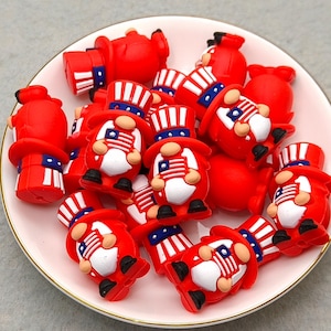 May include: A collection of red gnome figurines and fire hydrants on a white plate. The gnomes wear top hats and hold American flags. The hydrants have blue and white stripes.