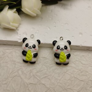 May include: Two white and black panda bear charms with green bamboo shoots. The charms have silver jump rings for attaching to jewelry.