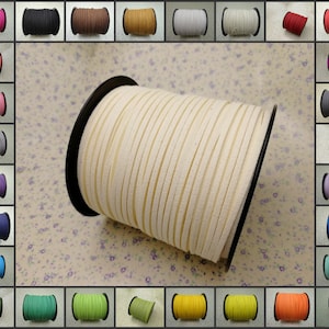 May include: A spool of off-white suede cord, approximately 3mm wide, is shown on a floral patterned background. The cord is wound around a black plastic spool. A variety of colors of the same cord are shown in smaller spools around the main image.