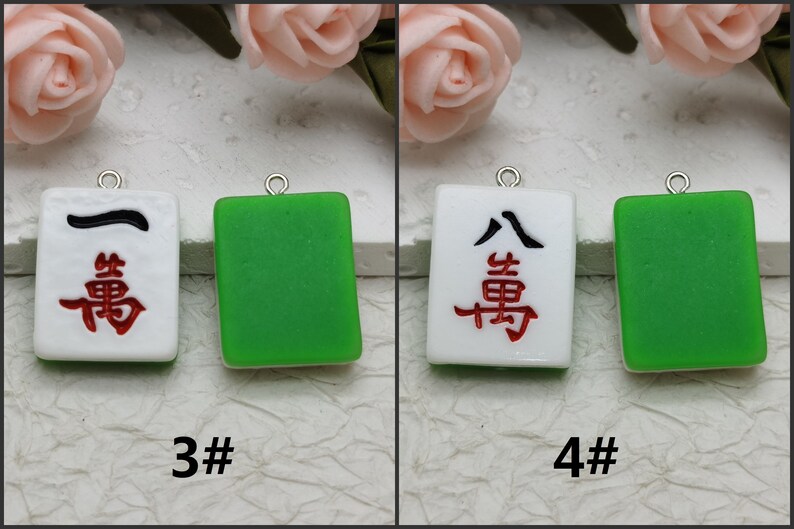 Puede incluir: Dos juegos de azulejos de cer&aacute;mica blanca y verde con caracteres chinos y una l&iacute;nea negra. Los azulejos cuelgan de lazos plateados. Los azulejos est&aacute;n etiquetados como 3# y 4#.