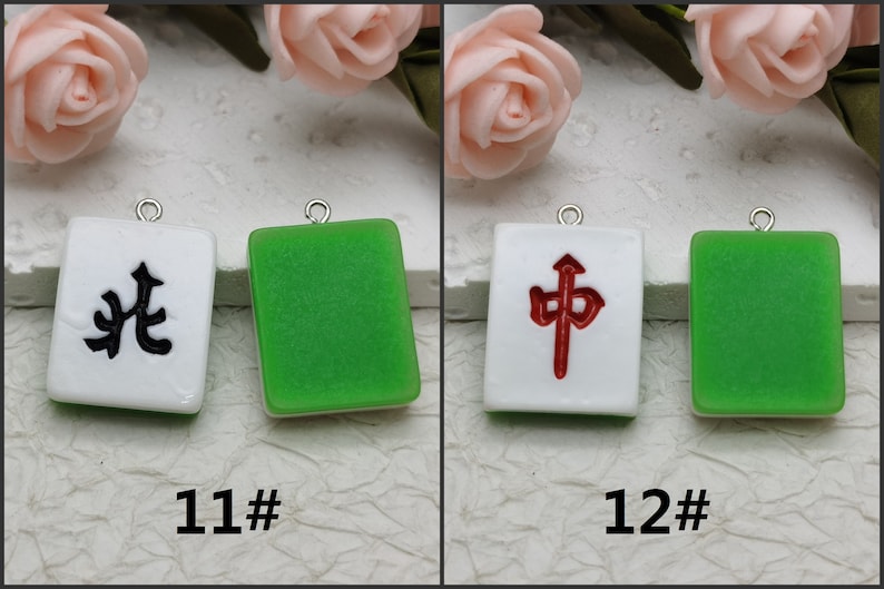 Puede incluir: Dos fichas de mahjong de cer&aacute;mica blanca con caracteres chinos negros y rojos. La ficha de la izquierda tiene un car&aacute;cter negro y la ficha de la derecha tiene un car&aacute;cter rojo. Ambas fichas tienen un borde verde.
