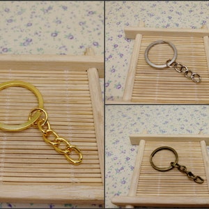May include: Three keychains with different finishes: gold, silver, and bronze. Each keychain features a circular ring and a chain.