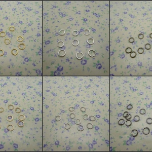 May include: Assortment of jump rings in gold, silver, and bronze. The jump rings are arranged in three rows on a floral patterned surface.