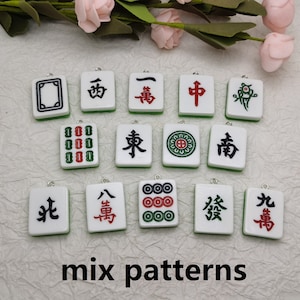 Puede incluir: Una colecci&oacute;n de 12 fichas de mahjong chinas blancas y verdes con varios s&iacute;mbolos y caracteres. Las fichas est&aacute;n dispuestas en tres filas de cuatro. Las fichas son todas diferentes, pero todas tienen un dise&ntilde;o similar. Las fichas miden aproximadamente 5 cm de largo y 2,5 cm de ancho.