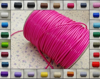 Puede incluir: Un carrete de cordón encerado de color rosa brillante, con una variedad de otros colores de cordón en el fondo.