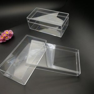 Puede incluir: Tres cajas rectangulares de plástico transparente con tapas. Las cajas están vacías y están sobre una superficie negra.