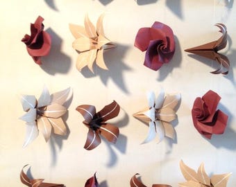 May include: An array of origami flowers in various colors, including brown, burgundy, and cream. The paper flowers are suspended, creating a decorative display. The flowers have detailed folds and shapes.