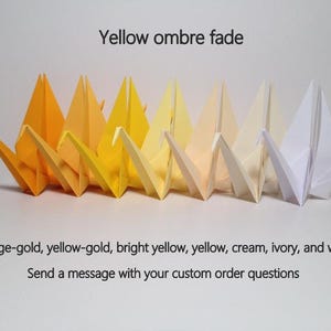 May include: A row of origami cranes in a yellow ombre fade, ranging from orange-gold to white. The text "Yellow ombre fade" is above the cranes. The text below reads "Orange-gold, yellow-gold, bright yellow, yellow, cream, ivory, and white".