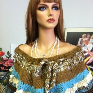 May include: A brown, blue, and white knitted shawl with a crocheted flower trim. The shawl is tied at the neck with a brown cord.