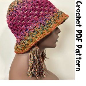 May include: A crocheted hat with a colorful ombre design and a long tassel. The hat is made with a stitch that creates a lacy effect. The hat is shown on a mannequin head. Crochet PDF Pattern.
