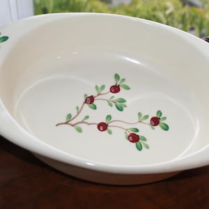 May include: Cream-colored oval serving dish with hand-painted cranberry and green leaf design. The dish has a smooth, glossy finish and is suitable for serving food. The cranberry design is on the rim and in the center of the dish.
