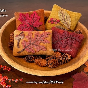 May include: Four small, rectangular pillows with autumn leaf designs in a wooden bowl. The pillows feature red, orange, and yellow leaves, with a brown acorn and leaf design. The text "Digital Pattern" is visible. The Etsy shop URL is also visible.