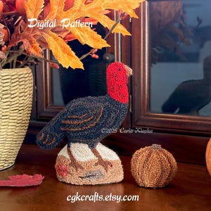 May include: A handcrafted turkey figurine with a red head and a black body, perched on a textured base. A small, round, brown pumpkin sits nearby. The image also includes a decorative vase with fall foliage and the text "Digital Pattern" and "cgkcrafts.etsy.com".