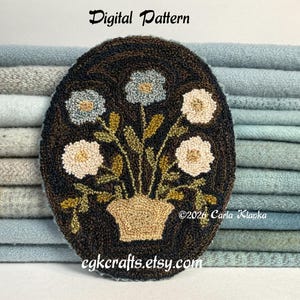 May include: An oval rug hooking piece featuring a dark brown background with a central tan vase containing five flowers in shades of light blue, cream, and white with green stems and leaves. Text reads Digital Pattern, 2026 Carla Klapka, cgkcrafts.etsy.com.