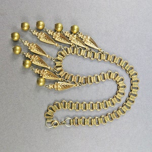 May include: A gold necklace with a chain and a pendant made of multiple gold beads and leaf-shaped charms.
