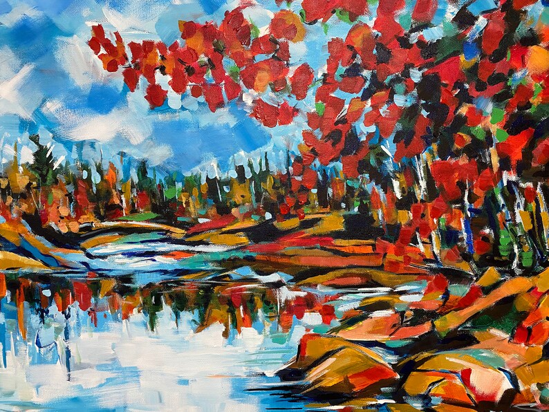 May include: A painting of a lake scene with a bright blue sky and red, orange, and yellow trees reflected in the water. The trees are on the right side of the painting, and the lake is in the foreground.