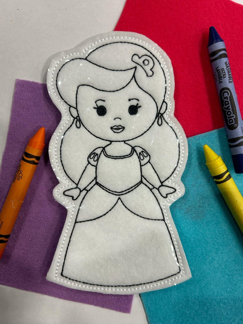 Pu&ograve; includere: Una bambola principessa di feltro bianco pronta per essere colorata. La bambola ha una corona, capelli lunghi, un vestito e un viso dolce.