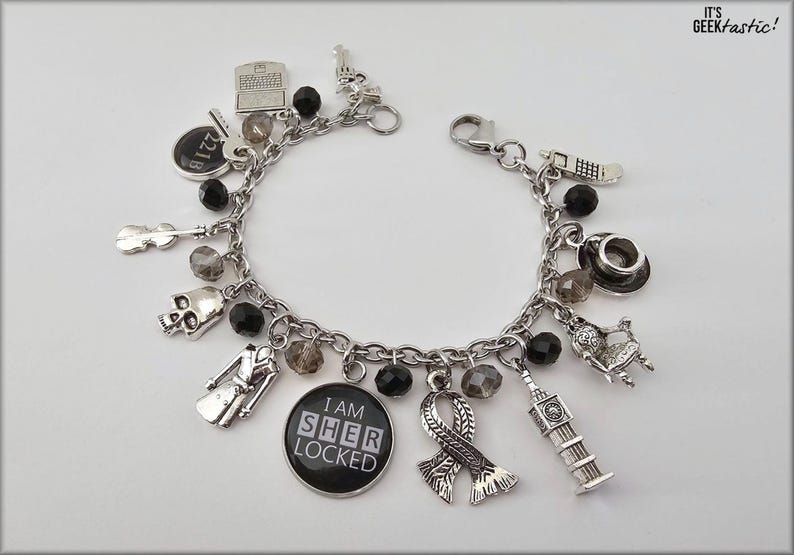 Puede incluir: Un brazalete de plata con cuentas negras y varios dijes, incluyendo una calavera, un viol&iacute;n, una cabina telef&oacute;nica de Londres, un sombrero, una silla, una bufanda, un edificio y un dije con el texto "I am Sher Locked".