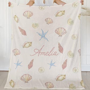Close-up of baby girl’s name in script font on seashell-themed blanket, perfect for custom newborn gifts