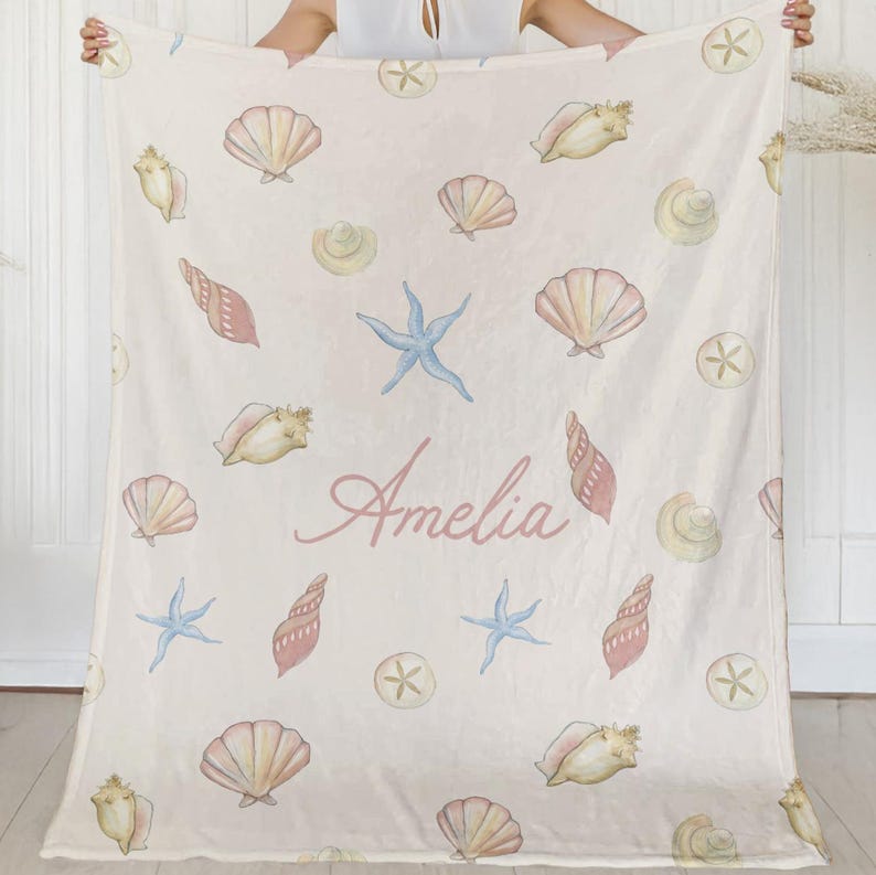 Close-up of baby girl’s name in script font on seashell-themed blanket, perfect for custom newborn gifts