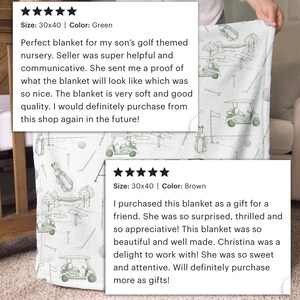 K&ouml;nnte beinhalten: Eine wei&szlig;e Decke mit einem gr&uuml;nen Golfplatzmuster, mit Golfwagen, Fahnen und Golftaschen. Die Decke misst 76 x 102 cm. Das Design wiederholt sich &uuml;ber den Stoff.