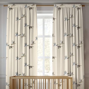 May include: A pair of cream-colored curtains featuring a repeating pattern of flying ducks in shades of brown, gray, and white. The curtains are gathered at the top on a rod, displaying vertical folds and a consistent print of birds in flight.
