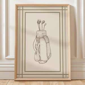 May include: A framed print featuring a detailed sketch of a golf bag with golf clubs. The artwork is in shades of beige and brown, with a light green border and a wooden frame. The image is a classic representation of golf equipment.