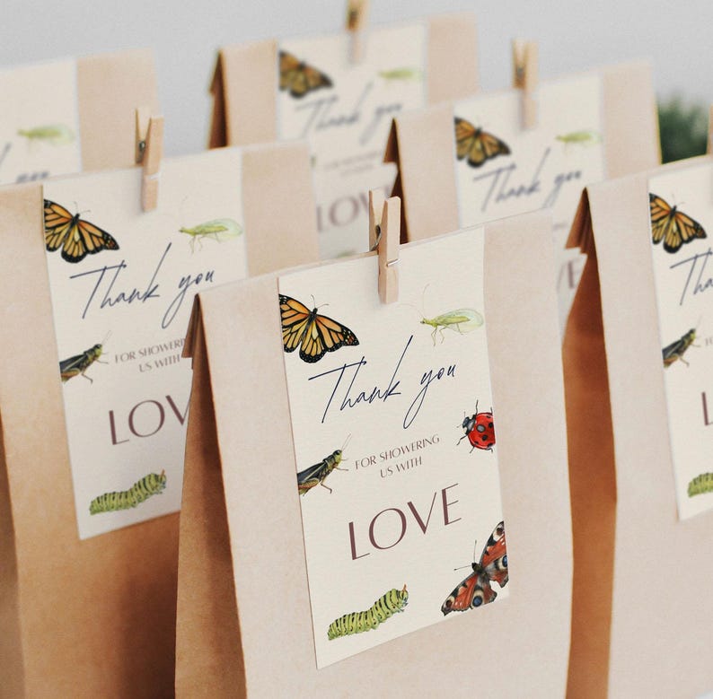 May include: Brown paper gift bags with tags that read "Thank you" and "Love." The tags feature watercolor illustrations of butterflies, insects, and caterpillars. The tags are attached with small wooden clothespins.