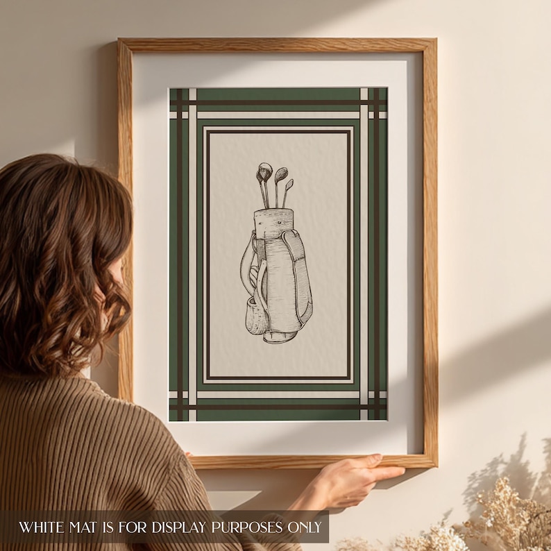 May include: A framed print featuring a detailed sketch of a golf bag with clubs. The artwork is set against a cream background, framed by a green and brown border, and encased in a light brown wooden frame. The text at the bottom reads: WHITE MAT IS FOR DISPLAY PURPOSES ONLY.