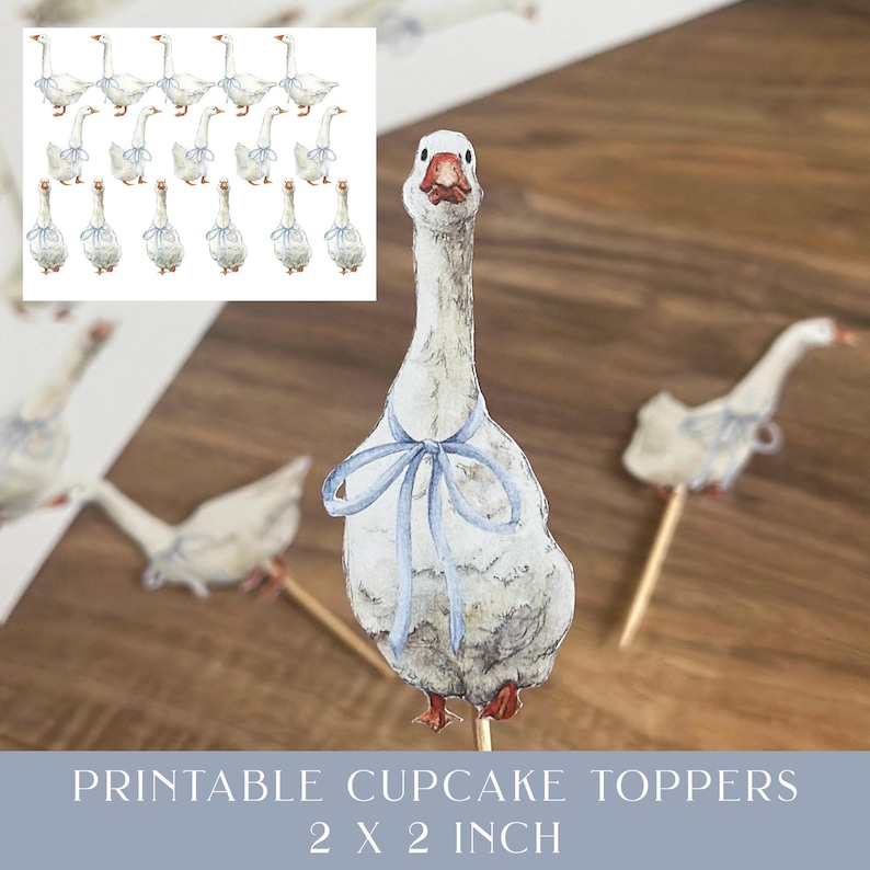 Op de afbeelding: Waterverf ganzen cupcake toppers met blauwe strikken. De afbeelding toont verschillende ganzen toppers op houten stokjes, met een vel extra toppers op de achtergrond. De tekst onderaan luidt "Printable Cupcake Toppers 5 x 5 cm."
