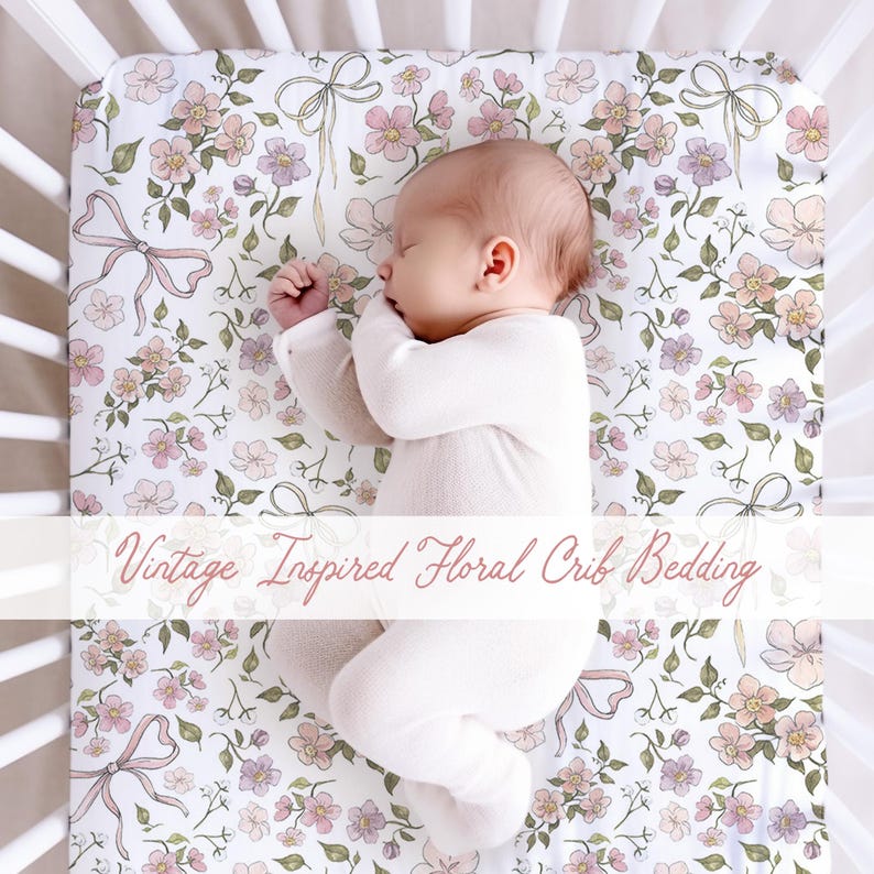 May include: A baby sleeps peacefully in a white crib on a floral patterned crib sheet. The sheet features pink, purple, and peach flowers with green leaves and pink bows on a white background. Text on the image reads "Vintage Inspired Floral Crib Bedding."