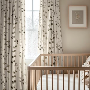 May include: Off-white curtains featuring a repeating pattern of dark brown animal tracks, including bird footprints, paw prints, and hoof marks. The curtains hang vertically beside a window, with a framed deer illustration on the wall.