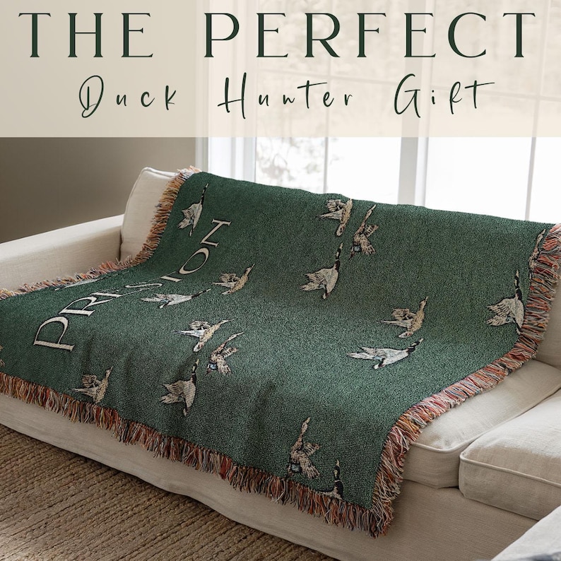 May include: A green woven throw blanket with a fringe border features a pattern of flying ducks. The blanket has the word "PRISON" woven into the fabric. The text "The Perfect Duck Hunter Gift" is displayed above the blanket.