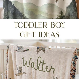 May include: A cream-coloured woven baby blanket with a green watercolour mountain scene and flying ducks. The blanket has a fringed edge and the name "Walter" is written in green cursive.