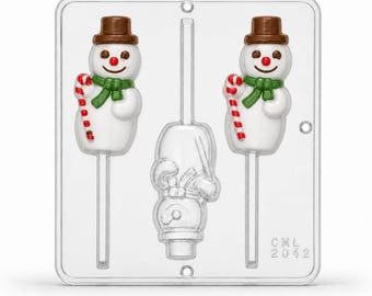 May include: A clear plastic candy mold featuring two snowman figures with brown hats, green scarves, and red and white candy canes, alongside a third inverted snowman shape. The mold is rectangular with rounded corners and marked with CML 2042.