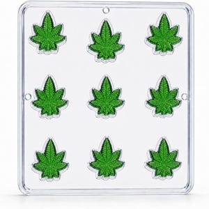 May include: A clear plastic rectangular mold featuring nine recessed cavities shaped like cannabis leaves. Each cavity has detailed vein patterns and a smooth finish, arranged in a three-by-three grid pattern within the transparent frame.