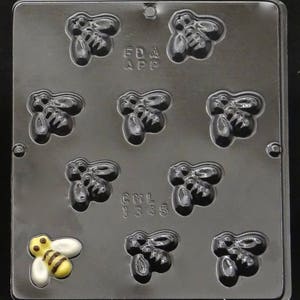 Peut inclure: Un moule en plastique noir avec huit cavités en forme d'abeille. Le moule est étiqueté "FDA APP" et "CNL 1335".