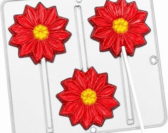 May include: A clear plastic candy mold featuring three flower-shaped cavities, each with a central yellow stamen and red petals. Two of the cavities contain finished red and yellow flower-shaped lollipops on white sticks, while one remains empty.